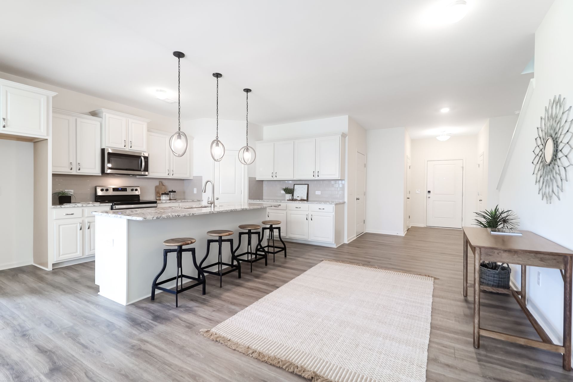 A kitchen and living room in a house with white cabinets and hardwood floors.
