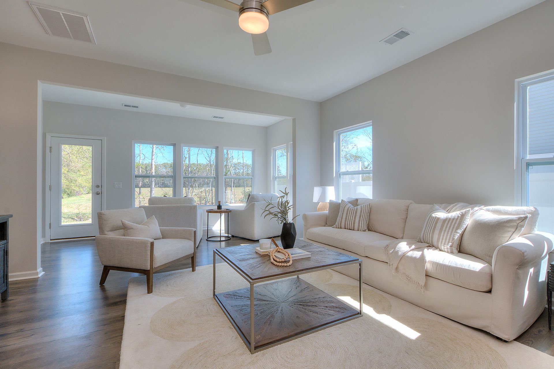 A living room with a couch , chair , coffee table and ceiling fan.