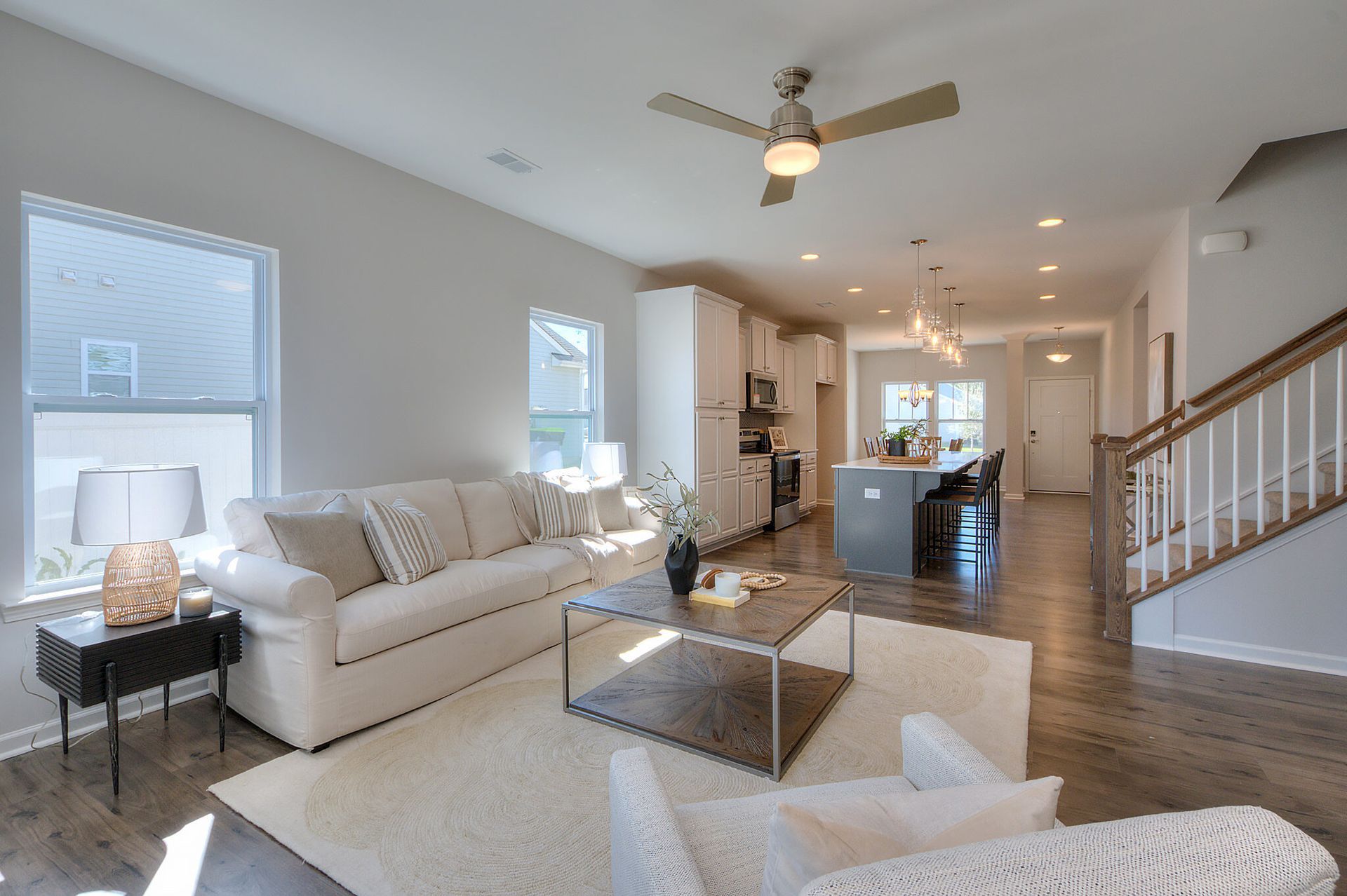 A living room with a couch , chairs , coffee table and ceiling fan.