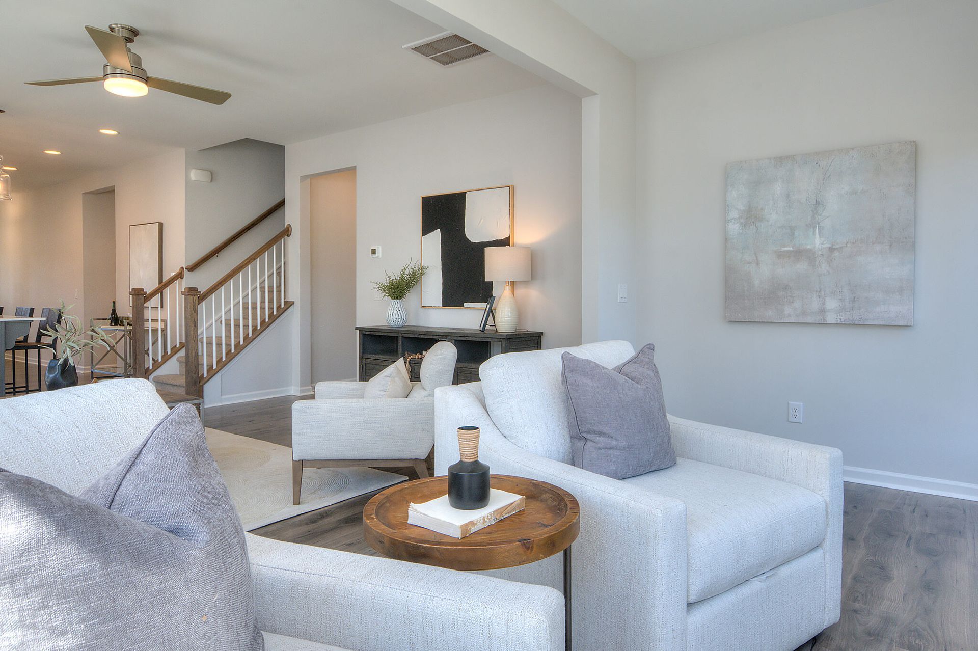 A living room with white furniture and a ceiling fan.