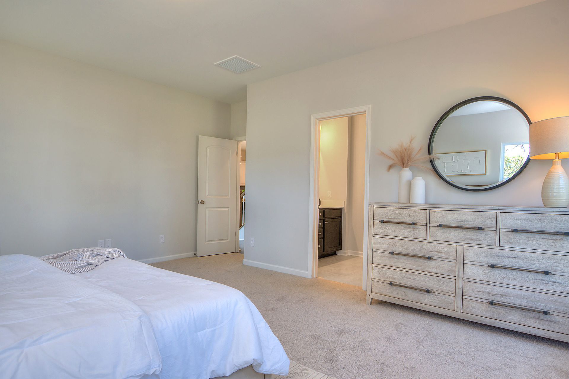 A bedroom with a bed , dresser and mirror.