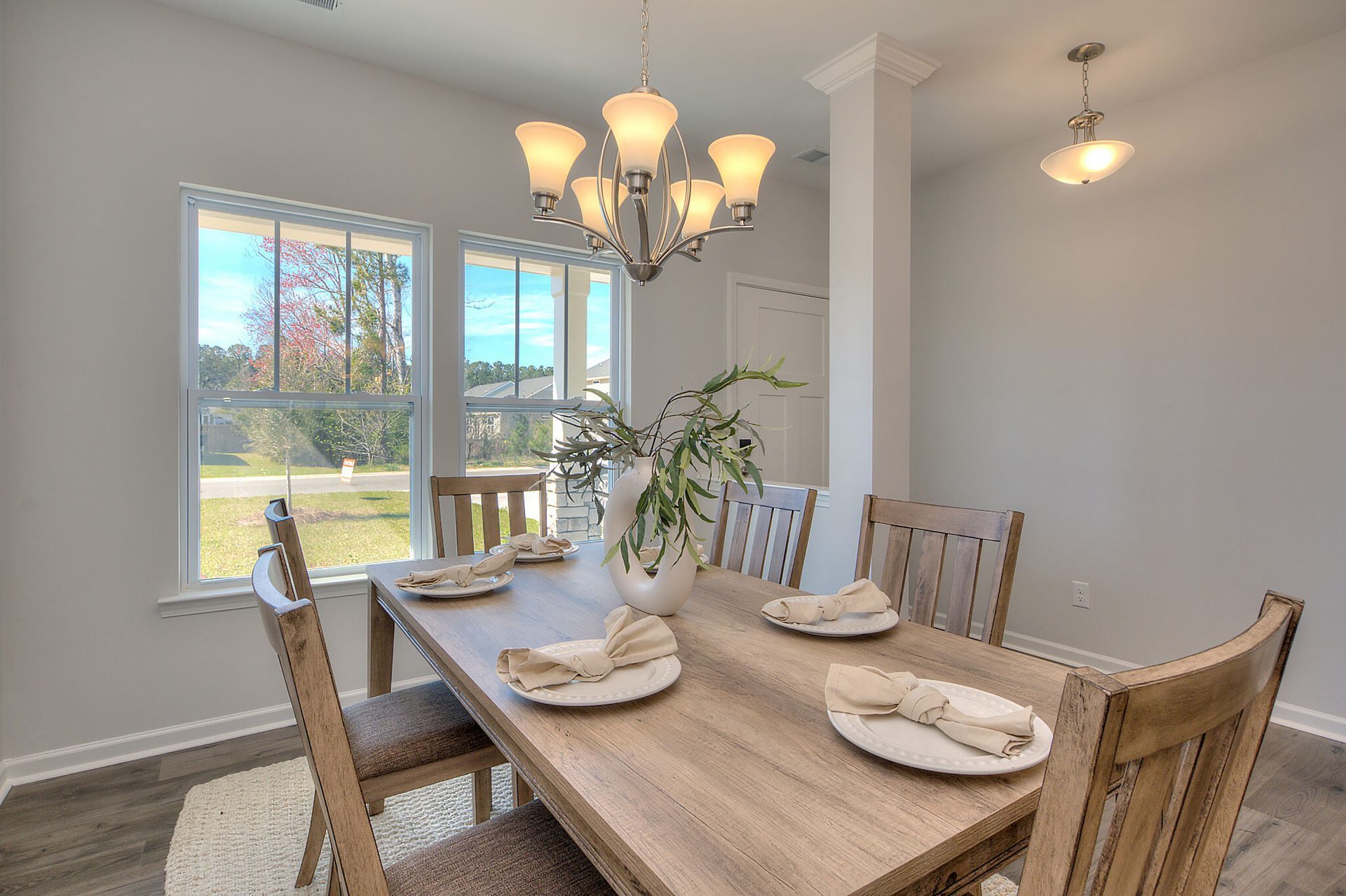 A dining room with a wooden table and chairs and a chandelier.