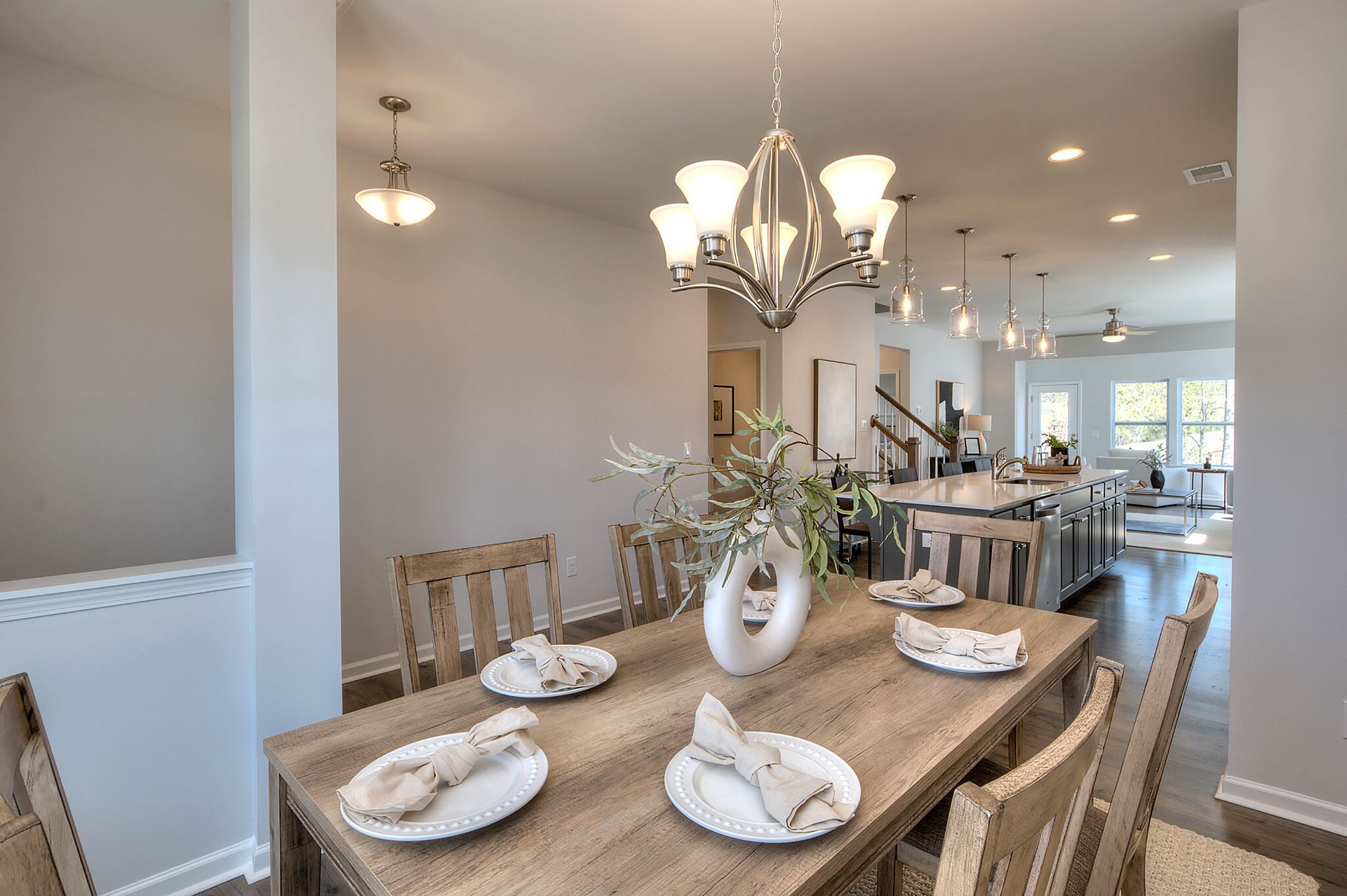 A dining room table with plates and napkins on it and a chandelier hanging from the ceiling.