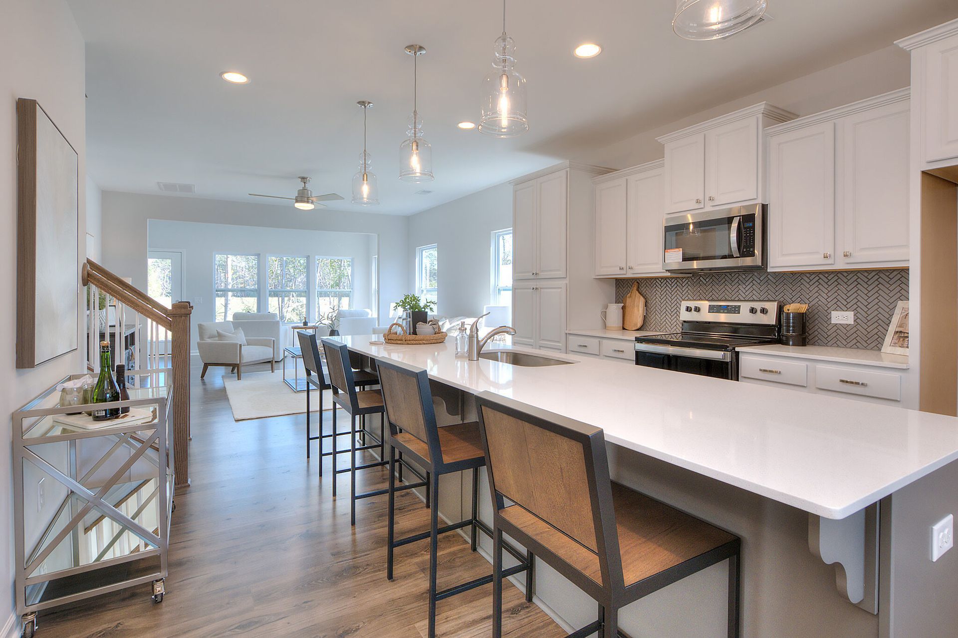 A kitchen with white cabinets , a large island , and stools.