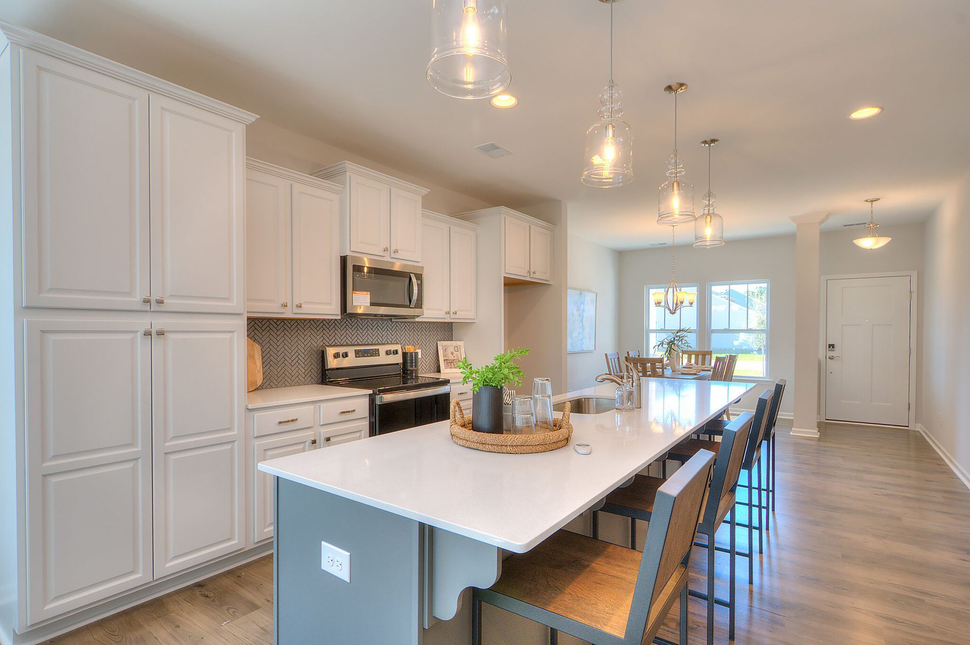 A kitchen with white cabinets , stainless steel appliances , and a large island.