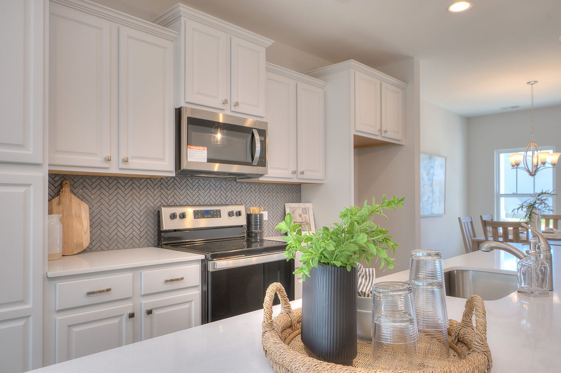 A kitchen with white cabinets , stainless steel appliances , a stove and a microwave.