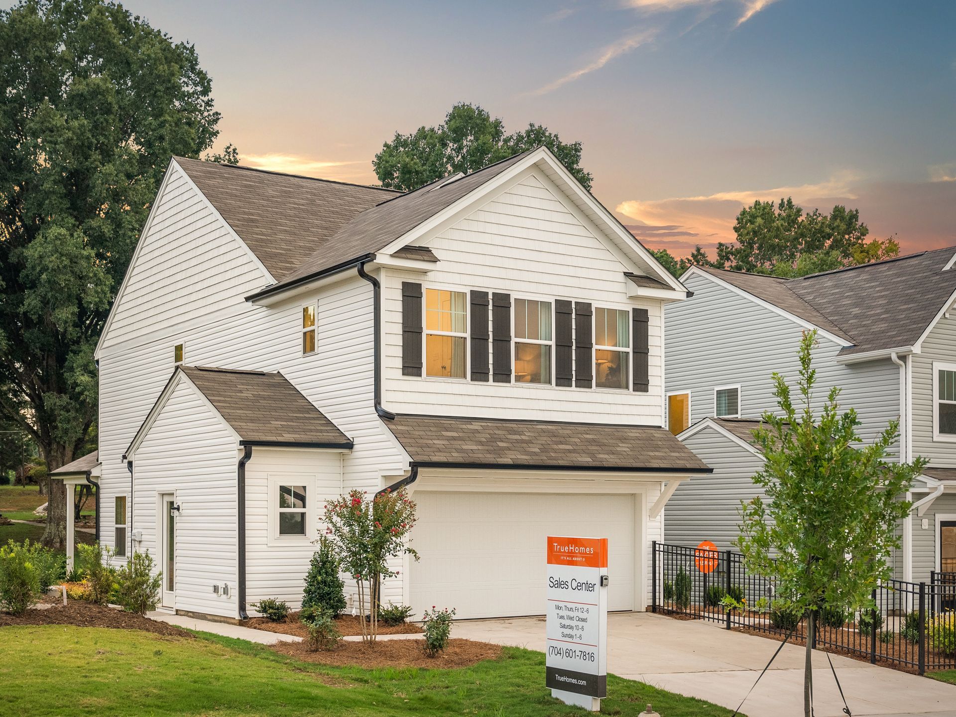 A white house with a sign in front of it for sale.