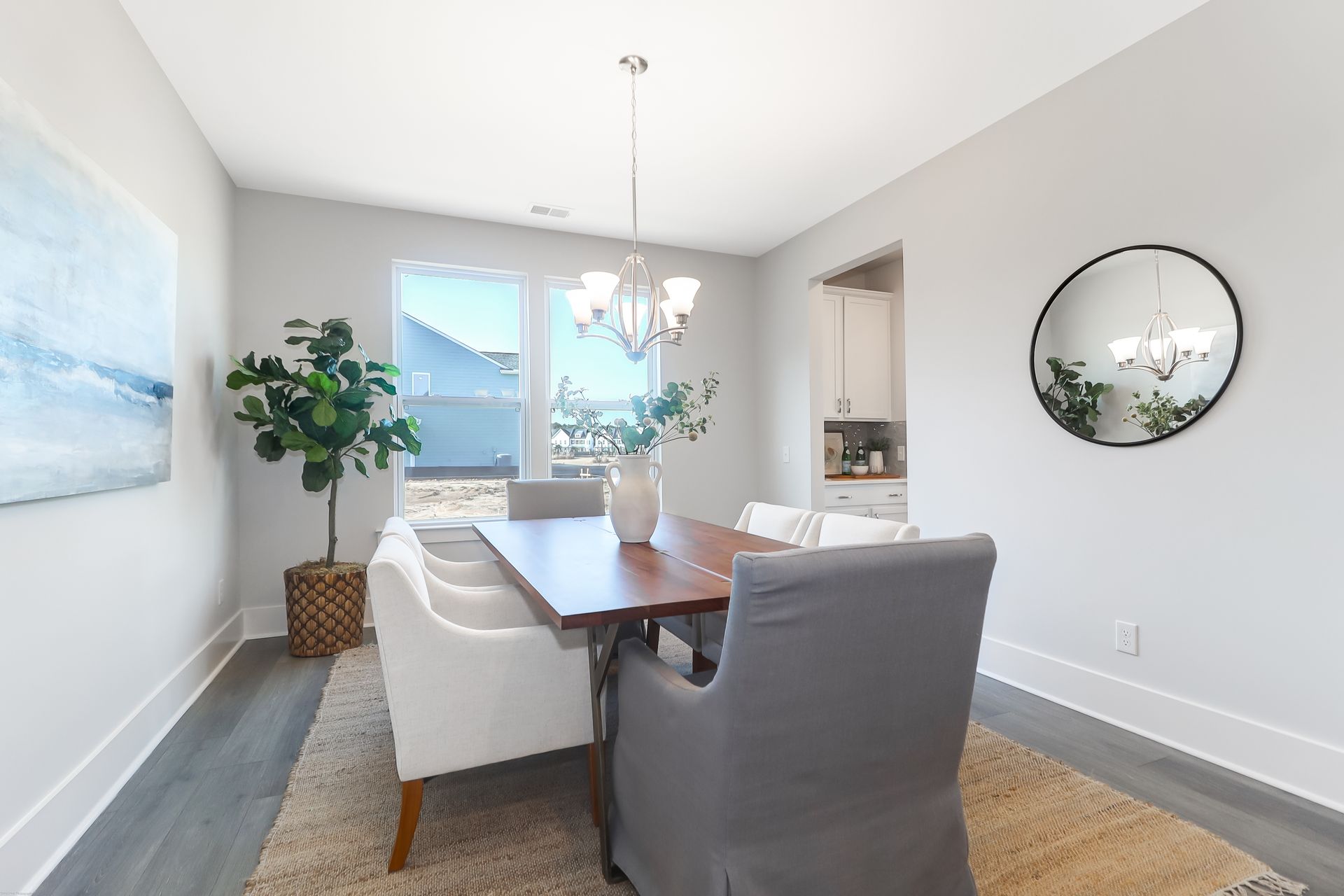 A dining room with a table and chairs and a mirror.