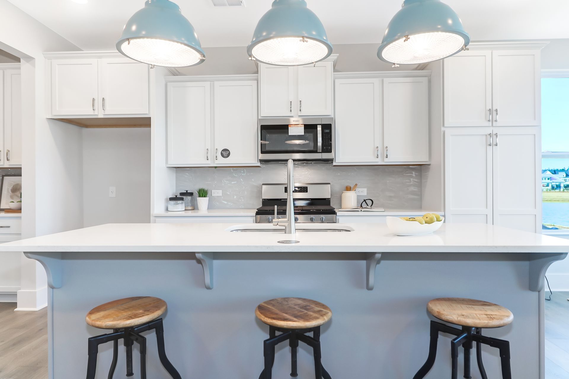 A kitchen with a large island and three stools.