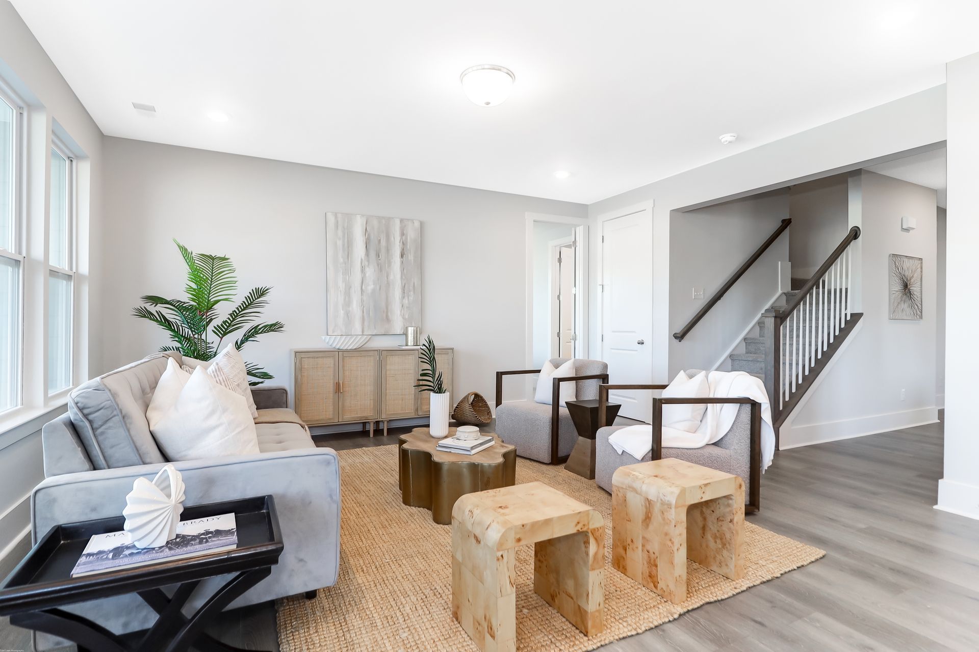 A living room with a couch , chairs , coffee tables and stairs.