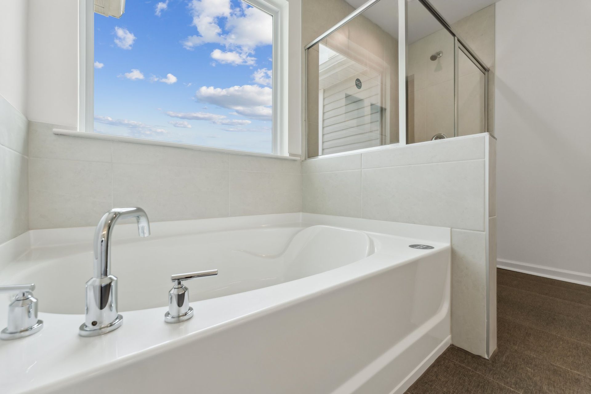 A bathroom with a bathtub , shower and window.