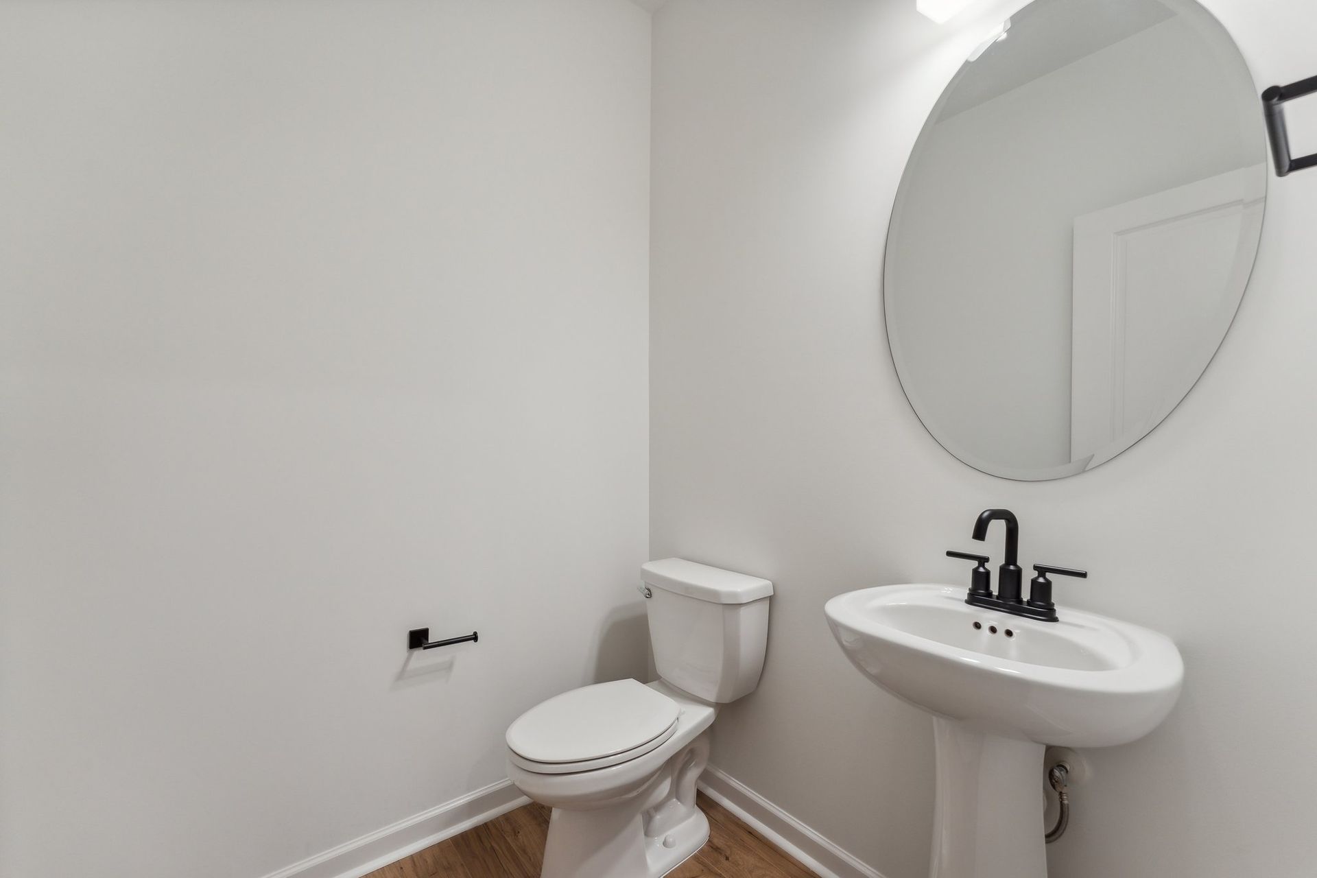 A bathroom with a toilet , sink and mirror.