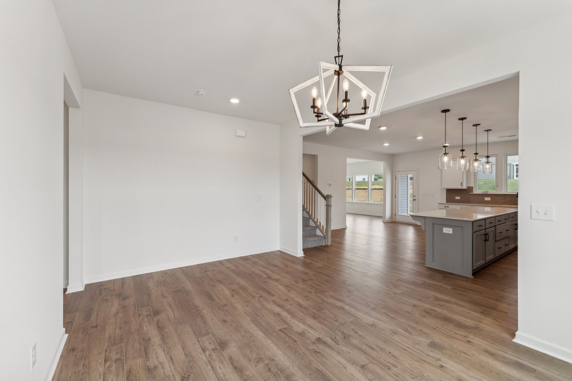 A living room with hardwood floors and a chandelier hanging from the ceiling.