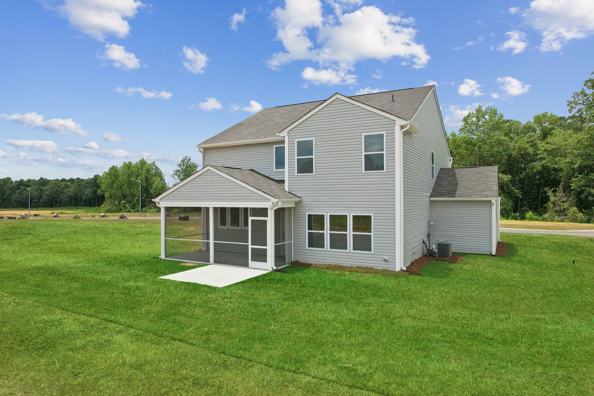 A large white house with a screened in porch is sitting on top of a lush green field.
