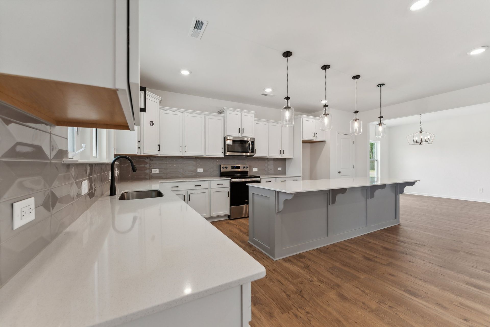 A kitchen with white cabinets , stainless steel appliances , and a large island.