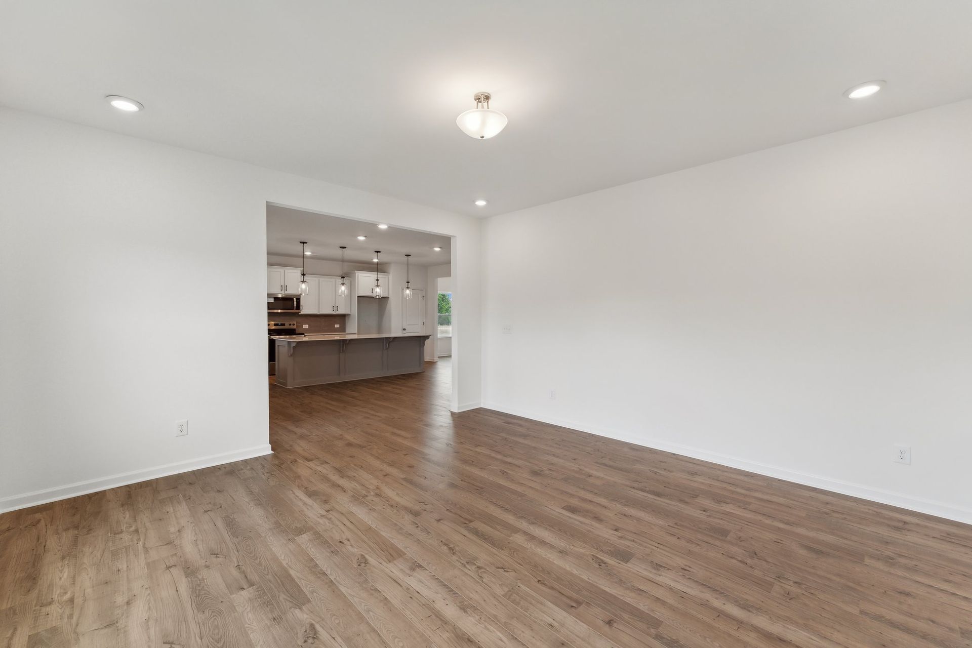 An empty living room with hardwood floors and white walls.