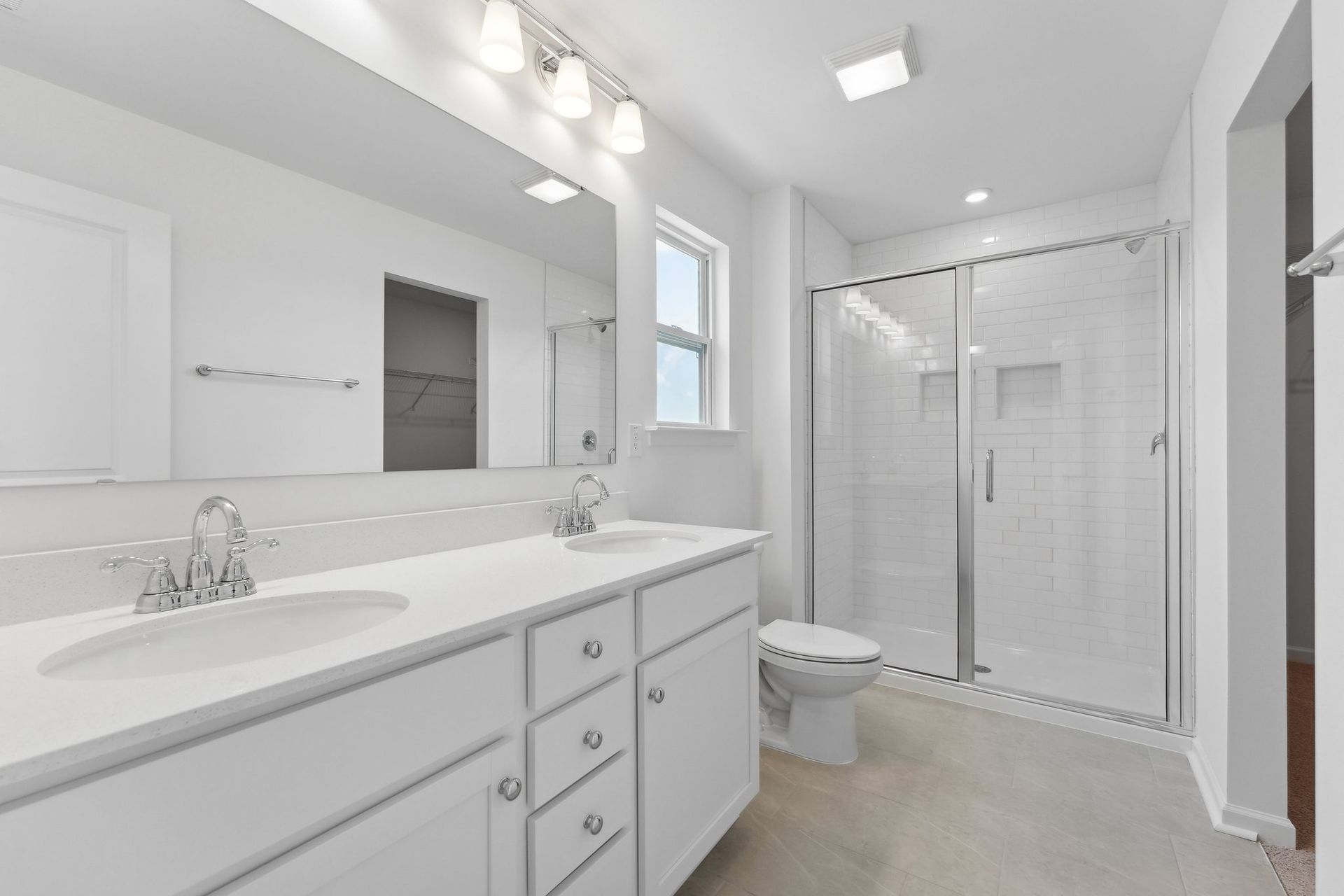 A bathroom with two sinks , a toilet , and a walk in shower.