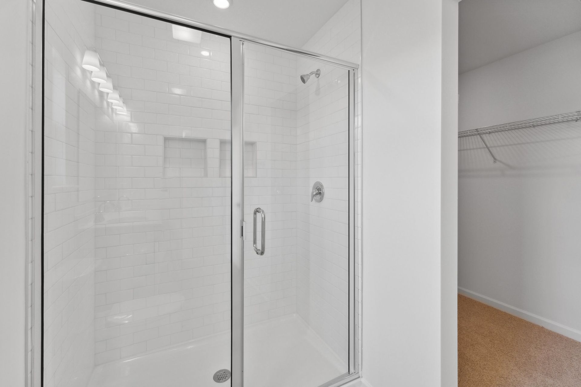 A bathroom with a glass shower door and a walk in closet.
