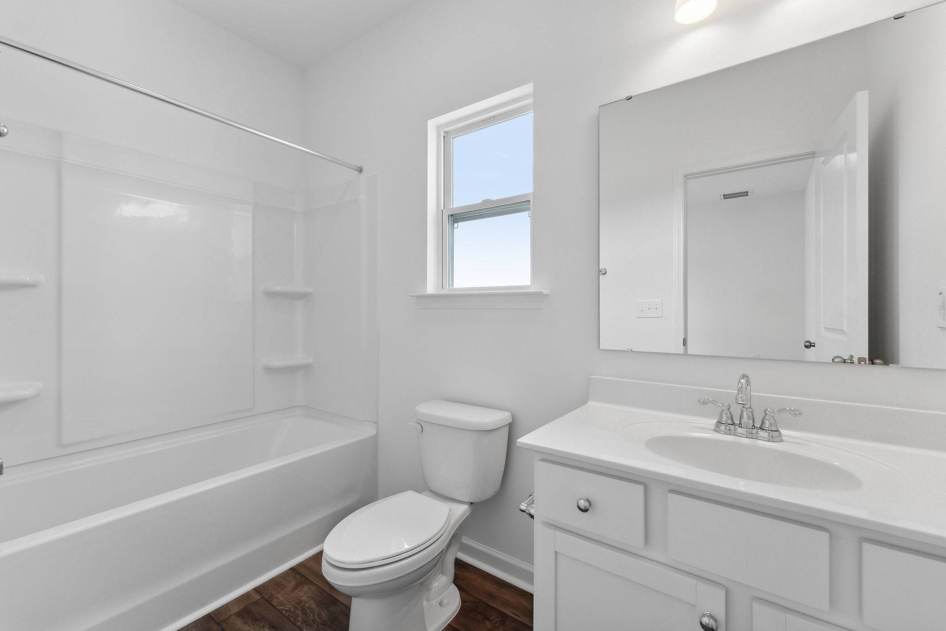 A bathroom with a toilet , sink , bathtub and mirror.