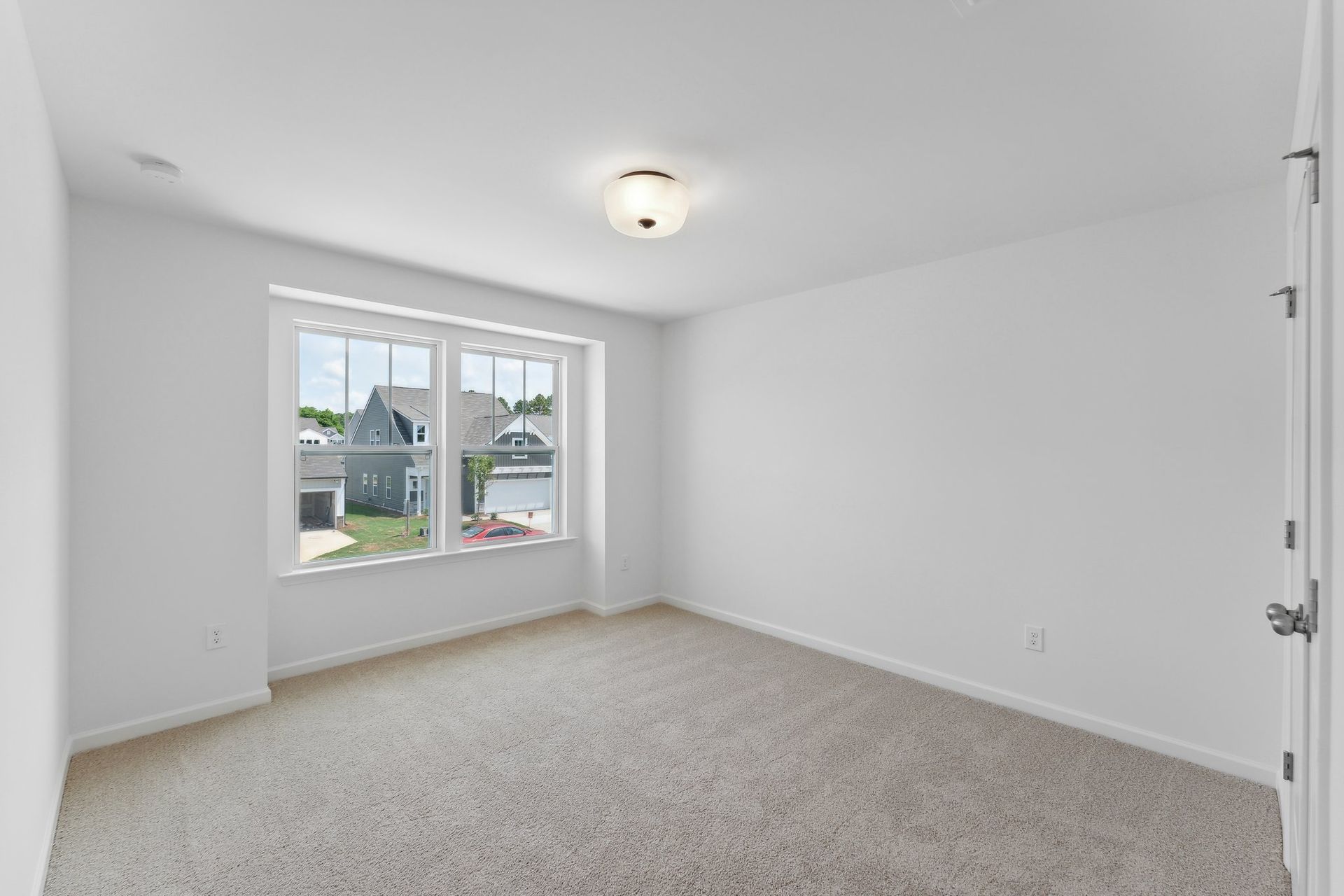 An empty bedroom with a large window and carpet.