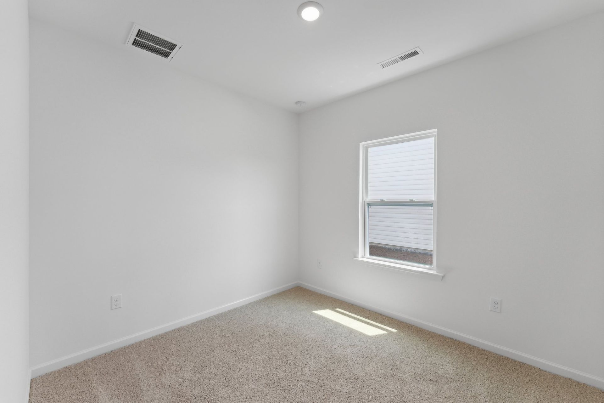 An empty bedroom with a window and carpet.