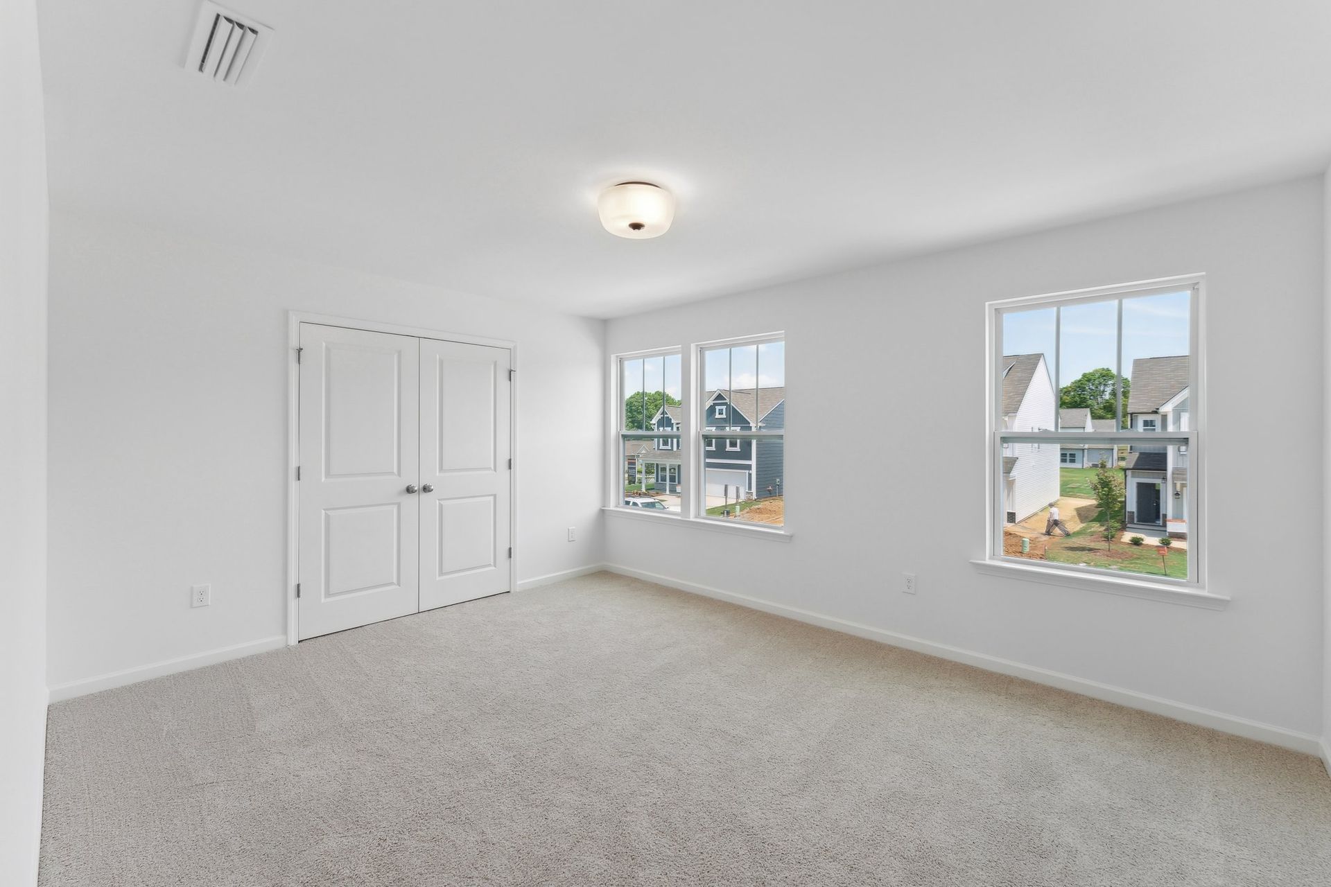 An empty bedroom with two windows and a closet.