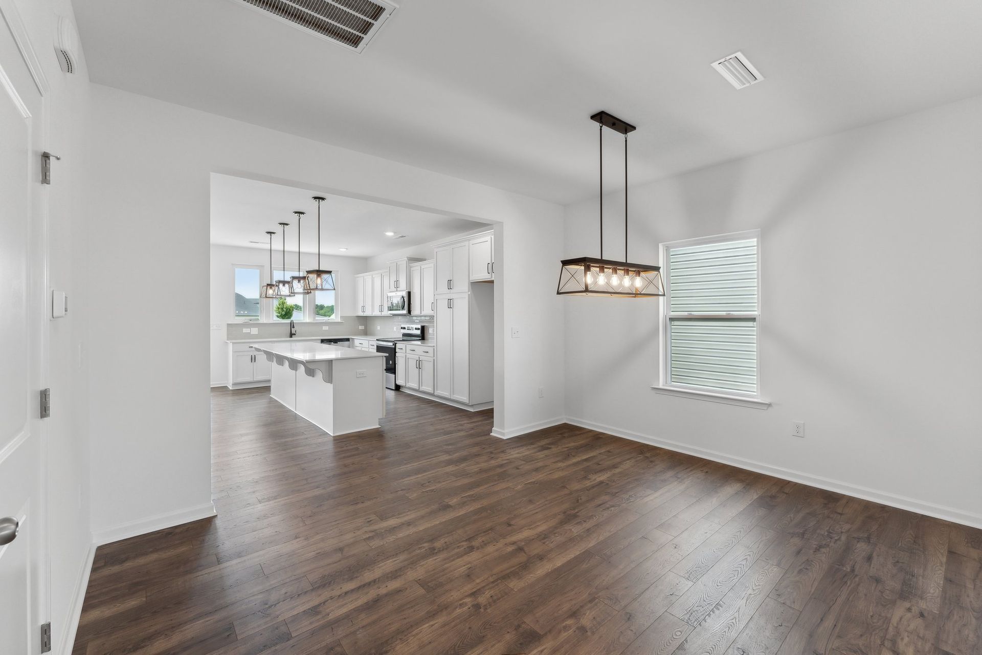A living room with hardwood floors and a chandelier hanging from the ceiling.