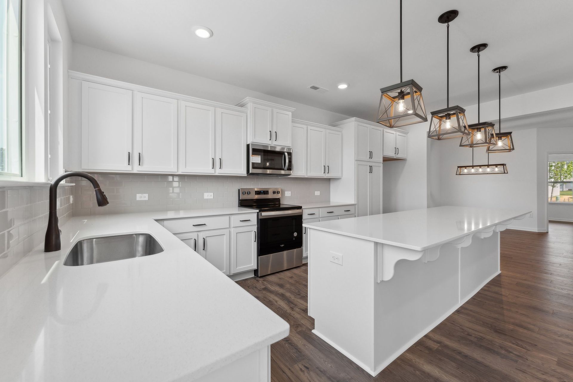 A kitchen with white cabinets , stainless steel appliances , and a large island.