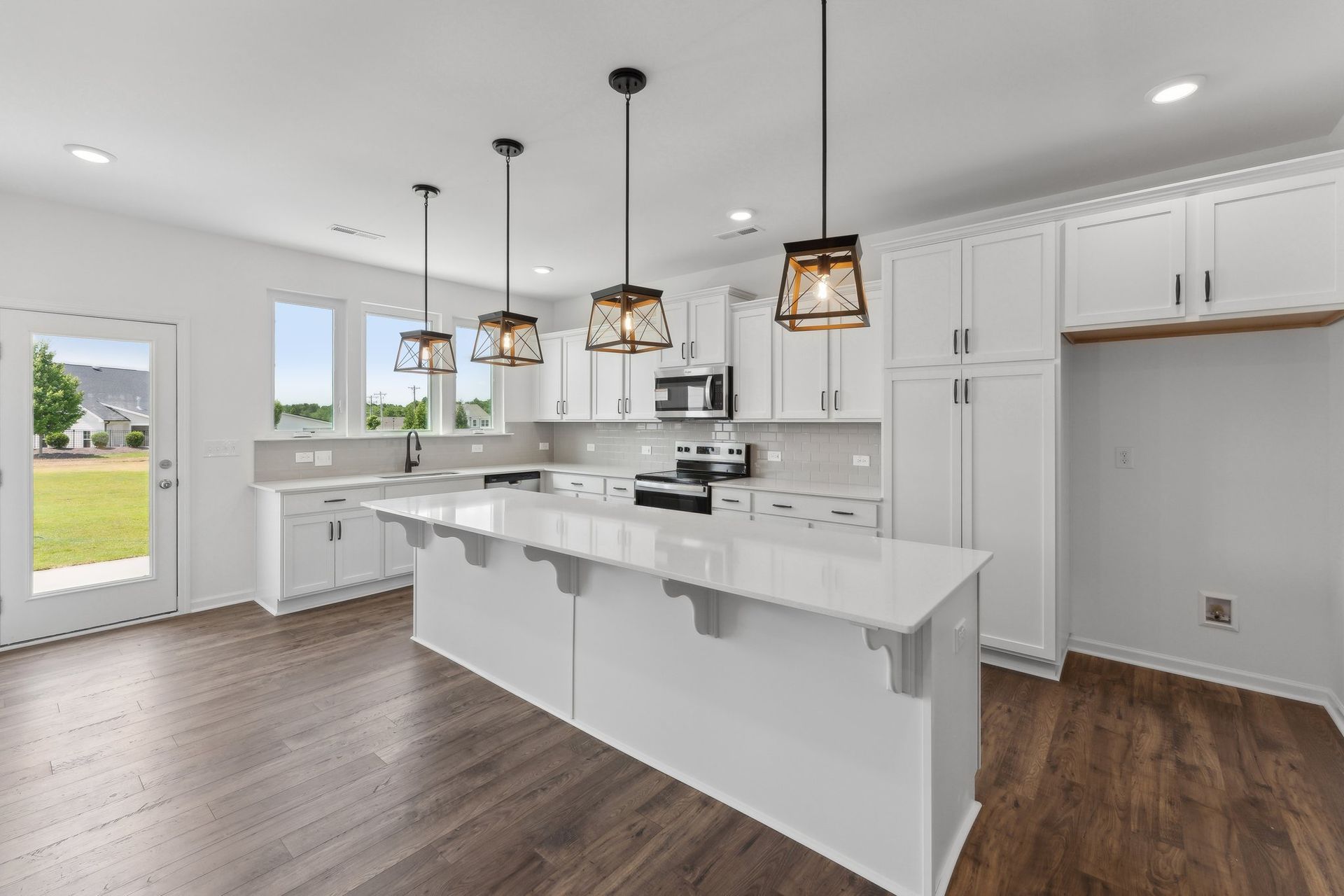 A kitchen in a new home with white cabinets and a large island.