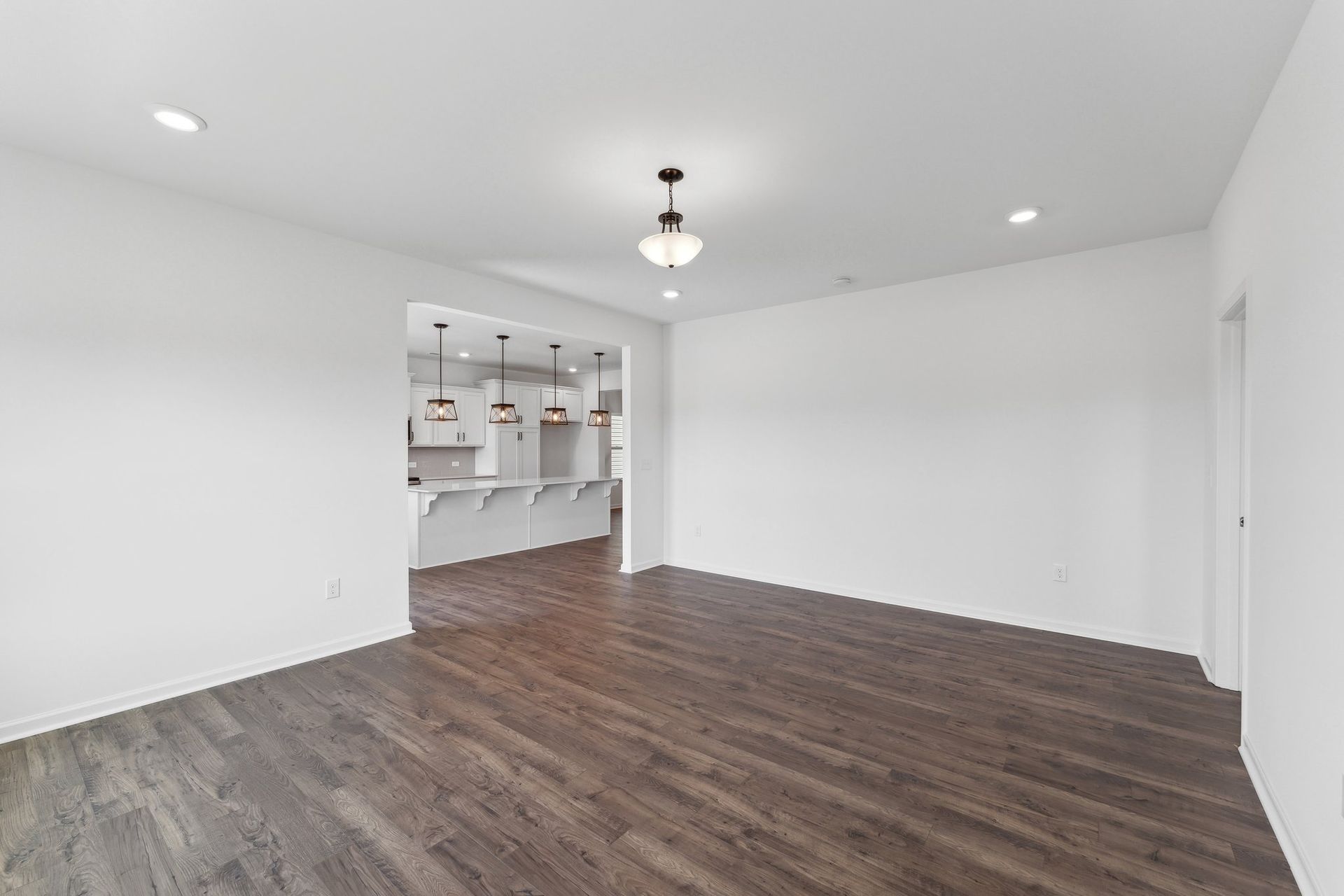 An empty living room with hardwood floors and white walls.