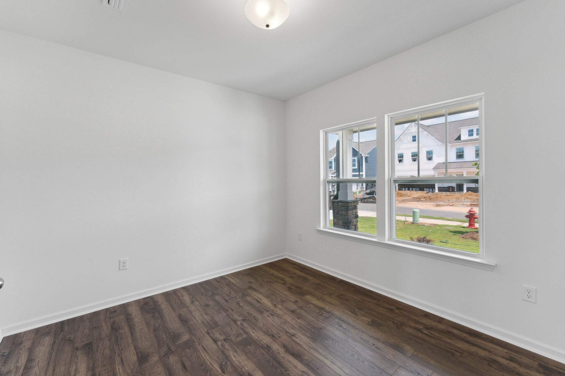 An empty room with hardwood floors and two windows.