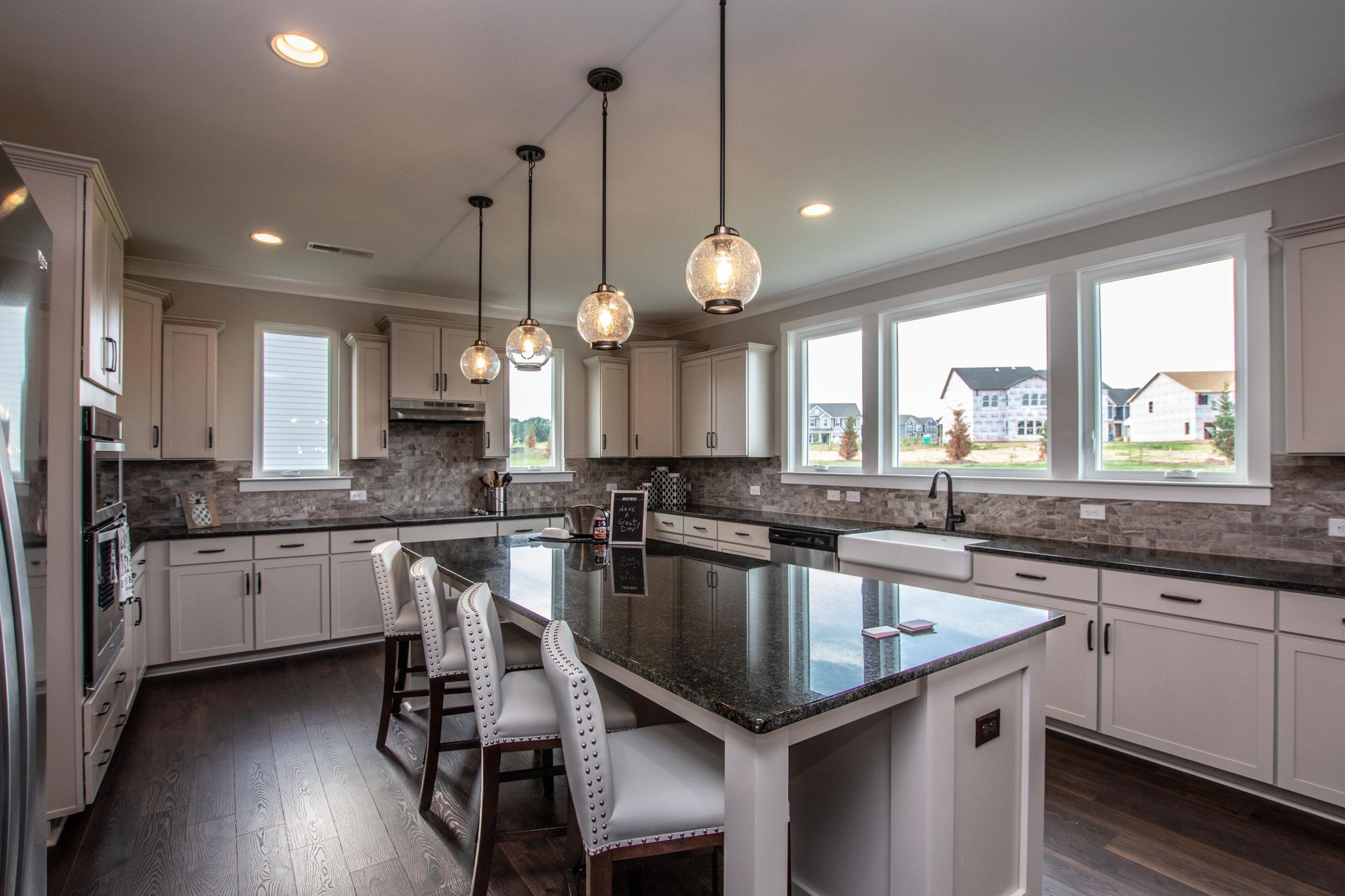 A kitchen with white cabinets , granite counter tops , and a large island.