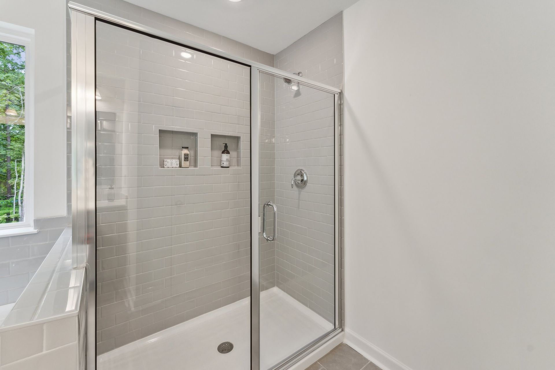 A bathroom with a walk in shower and a window.