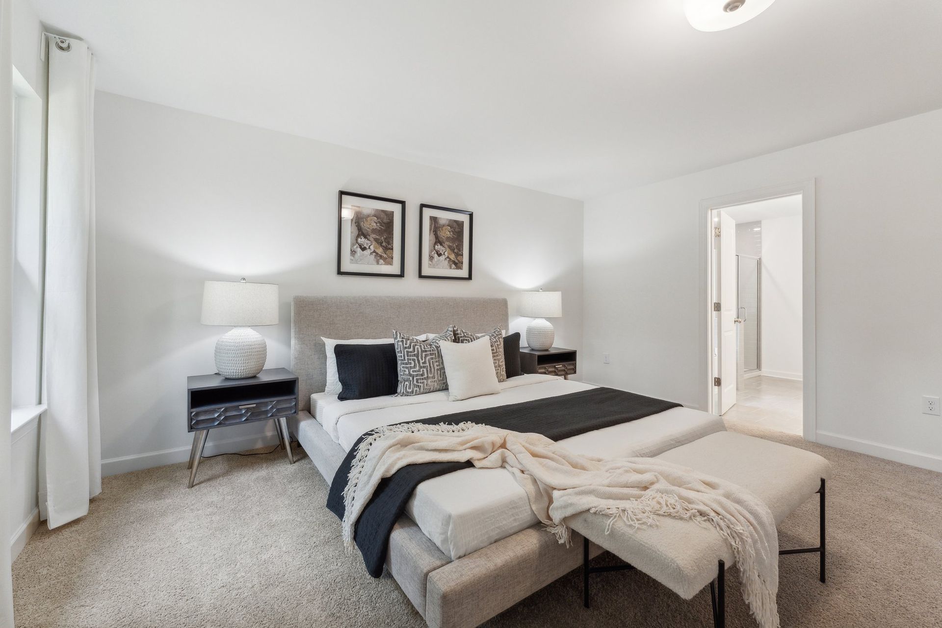 A bedroom with a king size bed , nightstands , lamps and a bench.