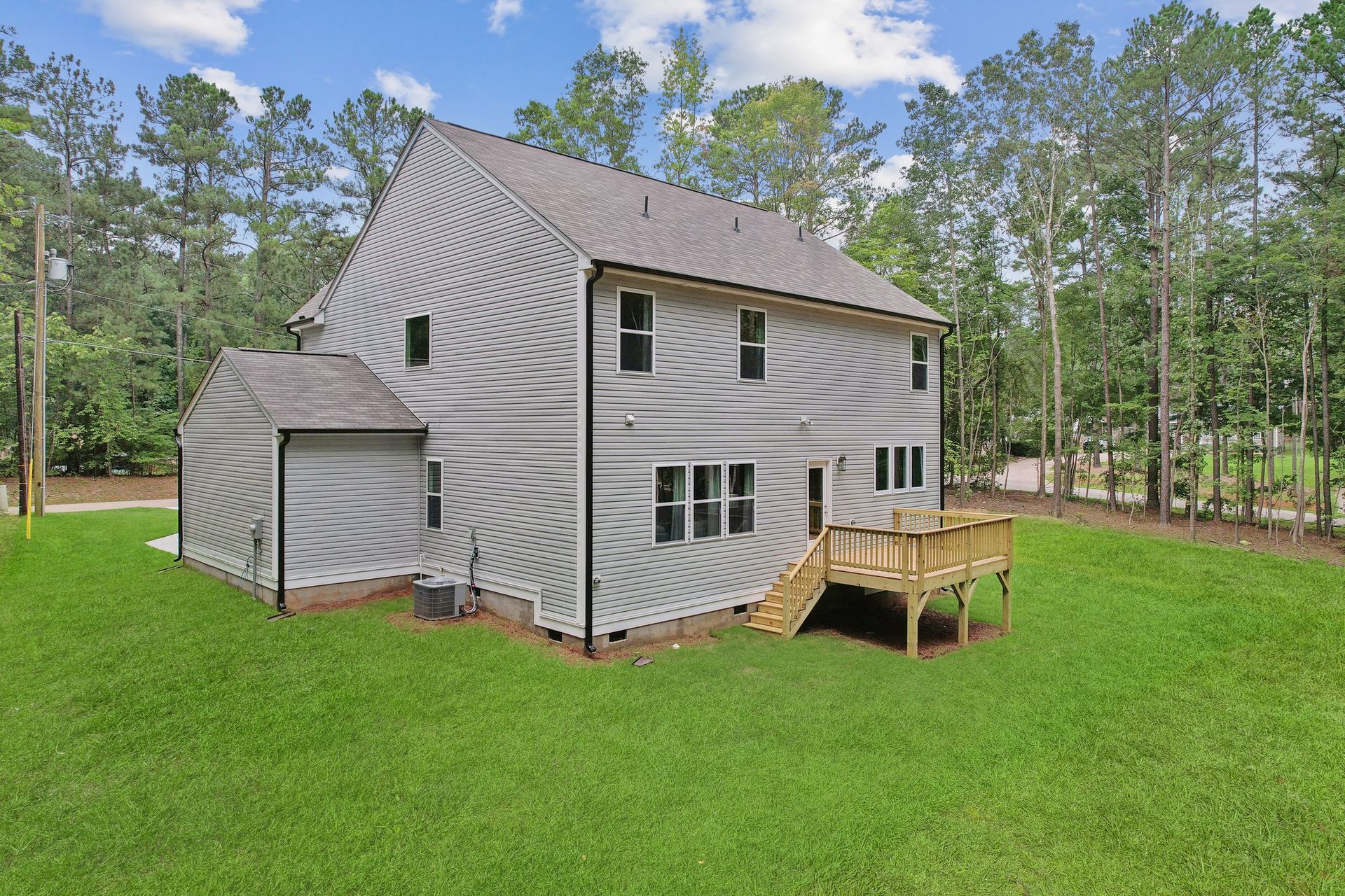 The back of a house with a deck and trees in the background.