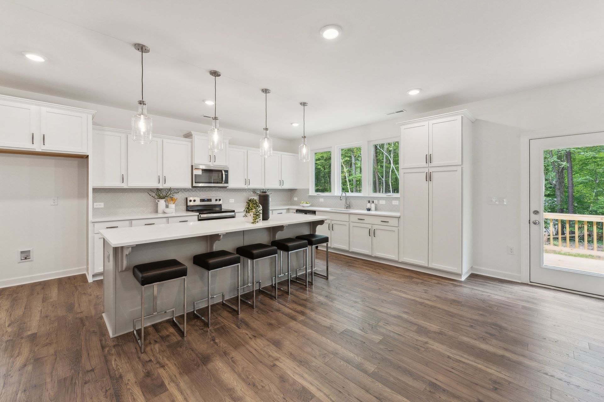 A kitchen with white cabinets and hardwood floors and a large island.