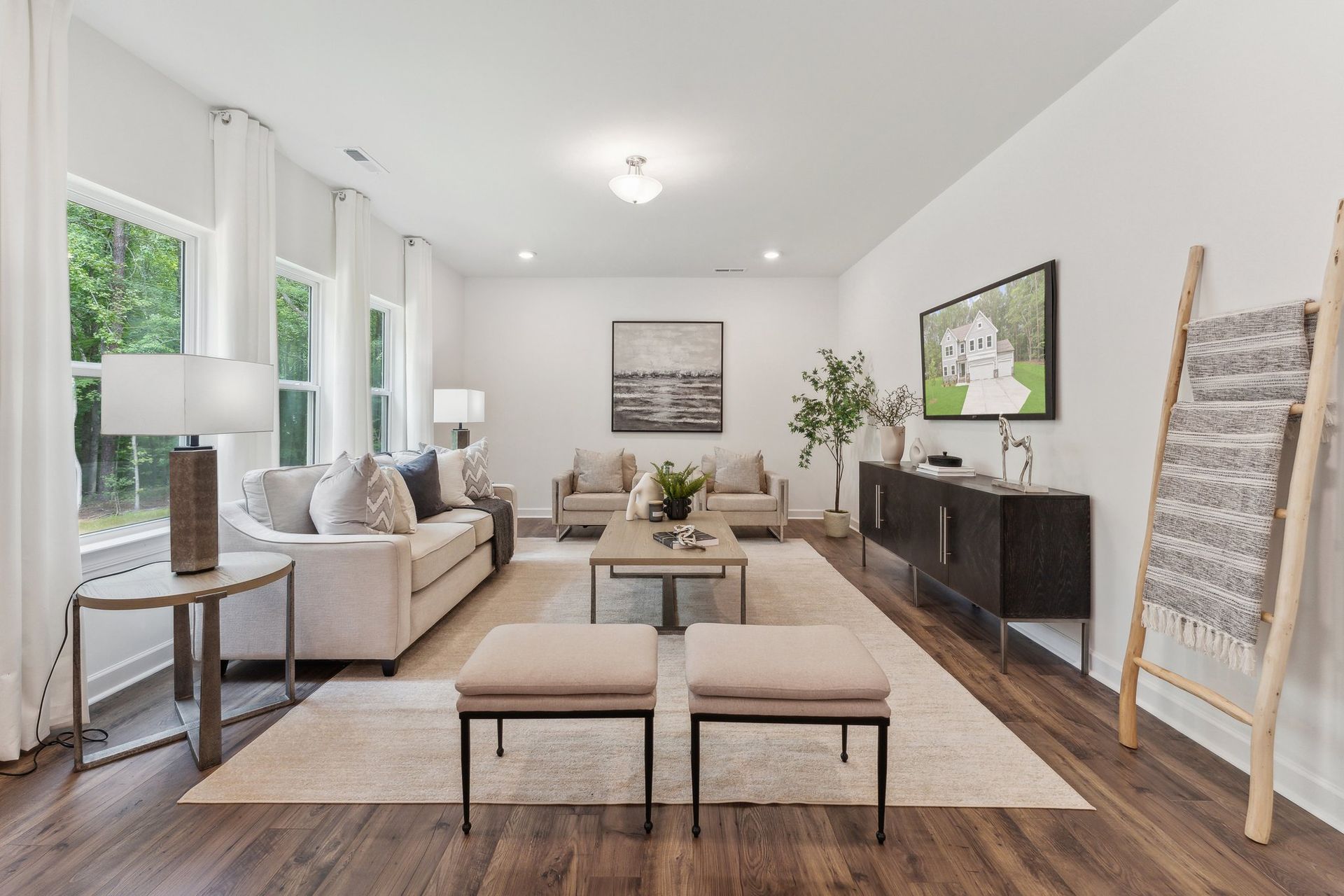 A living room with a couch , two ottomans , a table , and a television.