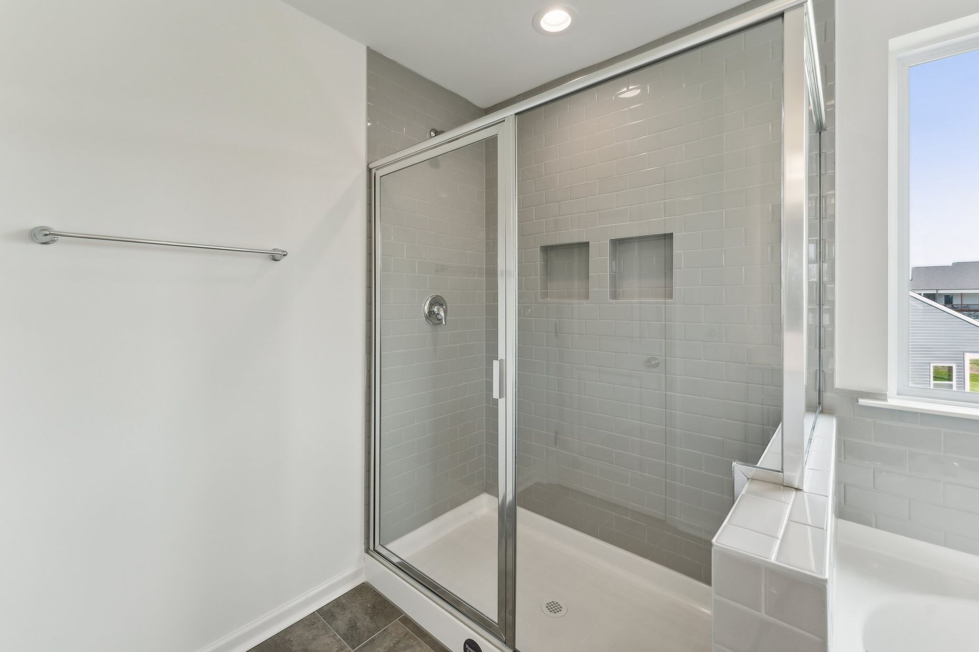 A bathroom with a walk in shower and a window.