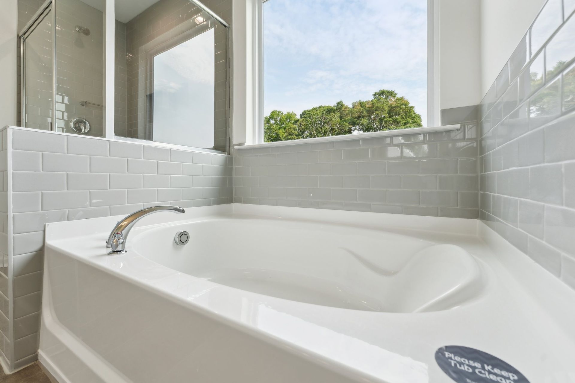 A white bathtub in a bathroom next to a window.
