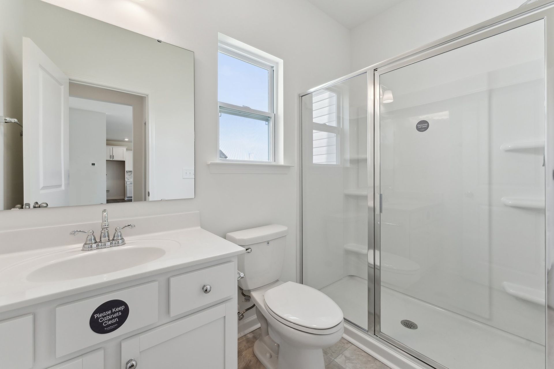 A bathroom with a toilet , sink , mirror and shower stall.