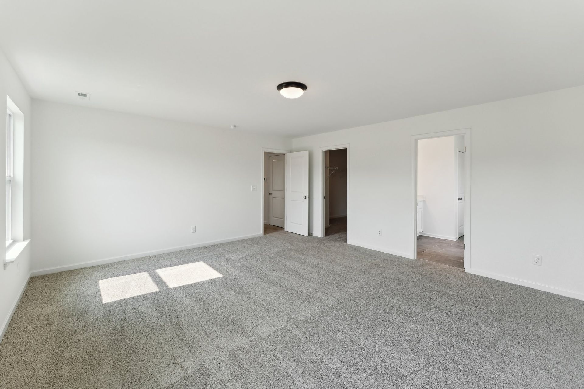A large empty room with a carpeted floor and white walls.