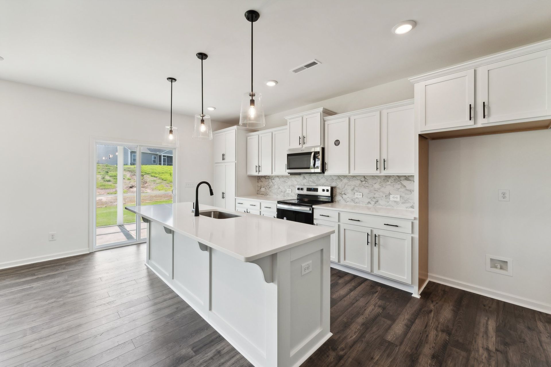 A kitchen in a new home with white cabinets and a large island.
