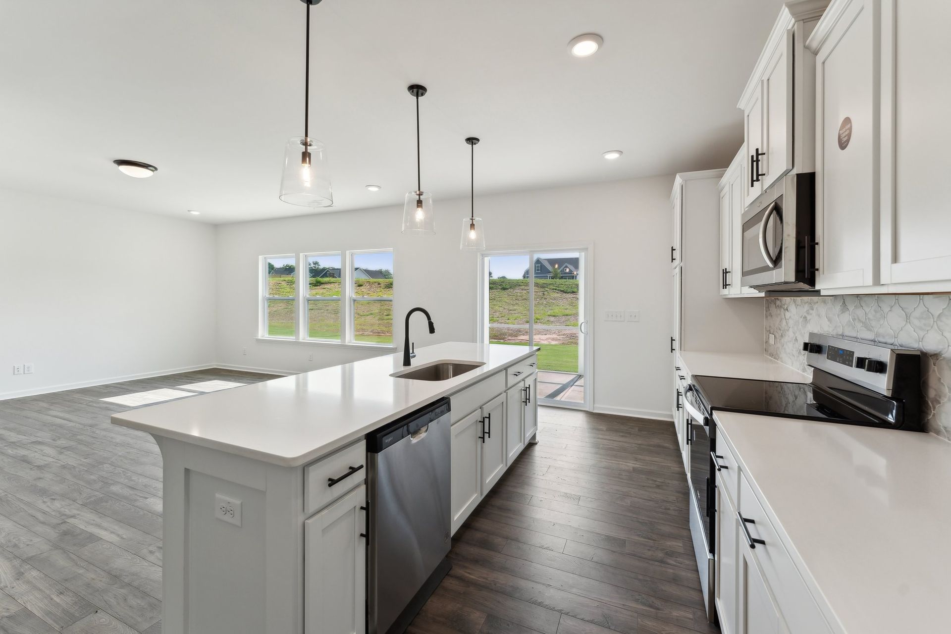 A kitchen in a new home with white cabinets and stainless steel appliances.