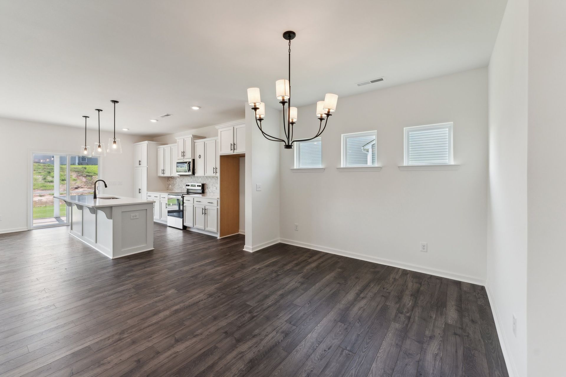 A living room with hardwood floors and a chandelier in a house.