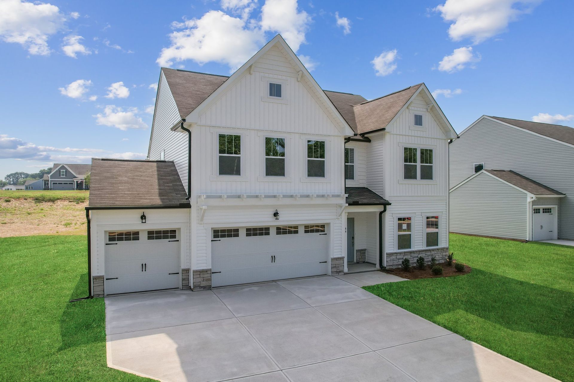 A large white house with two garages and a driveway.