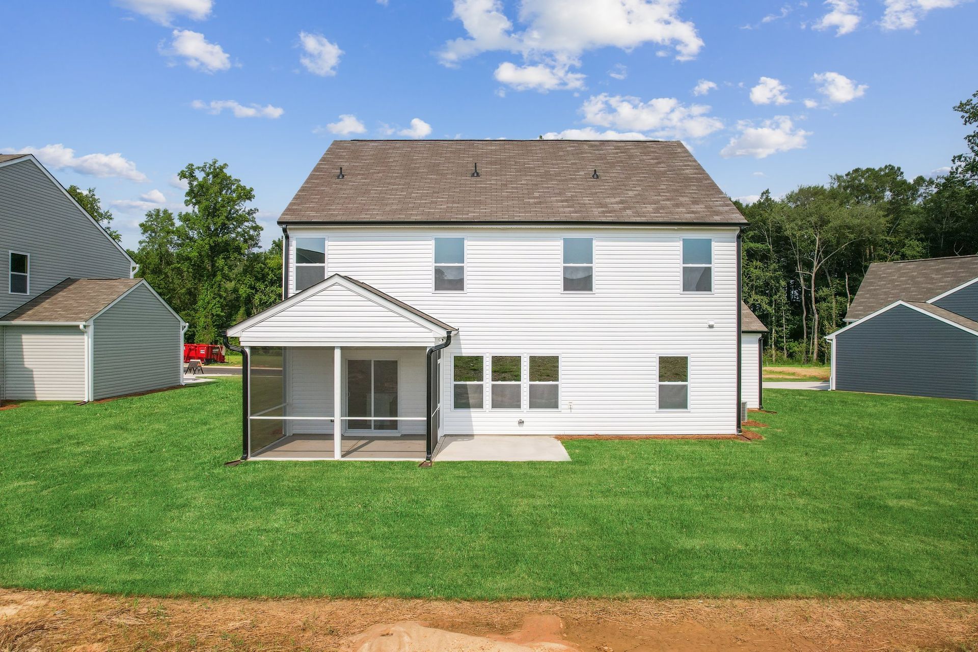 A large white house with a screened in porch is sitting on top of a lush green lawn.