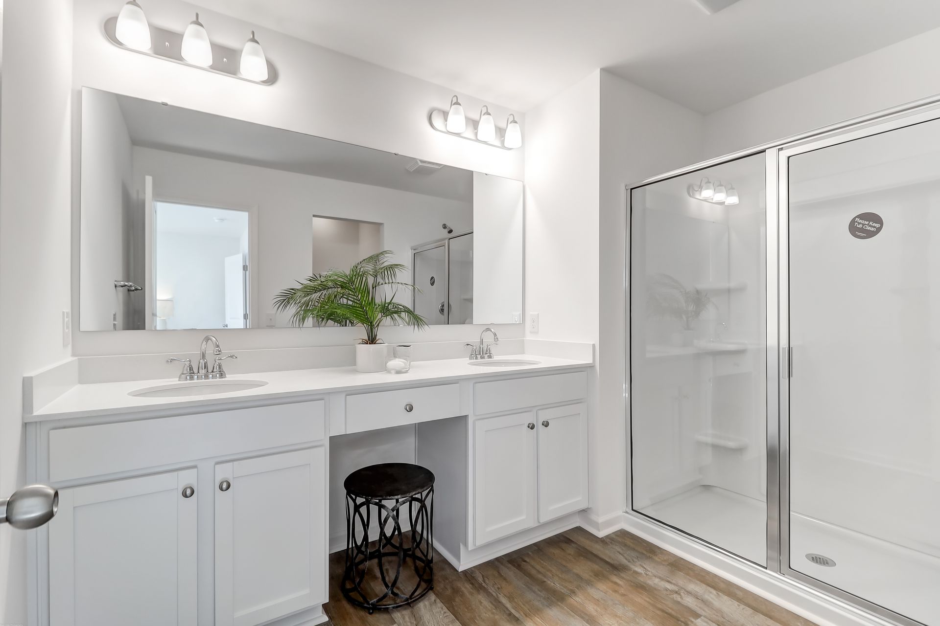 A bathroom with two sinks , a shower , and a large mirror.
