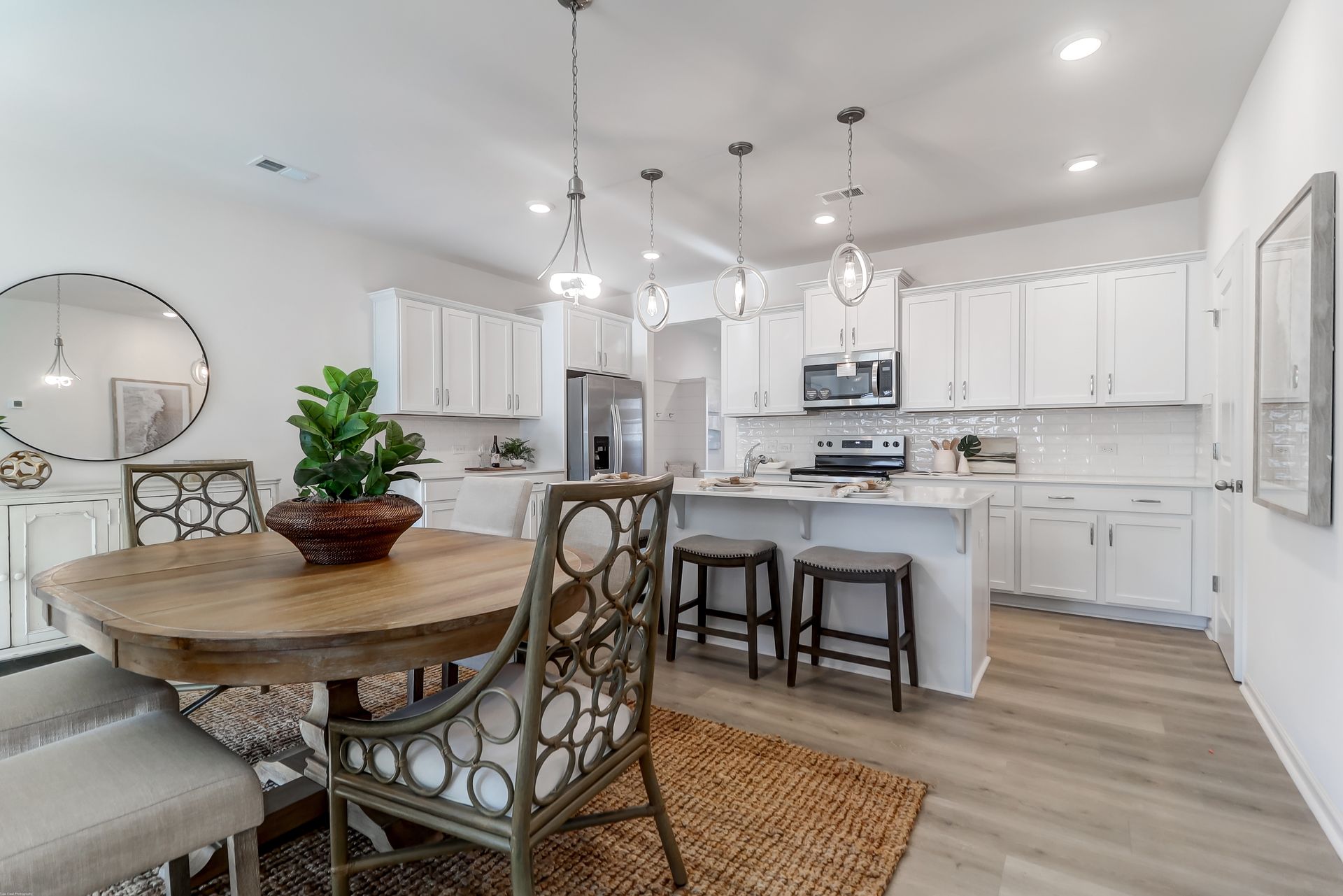 A kitchen and dining room in a model home with a table and chairs.