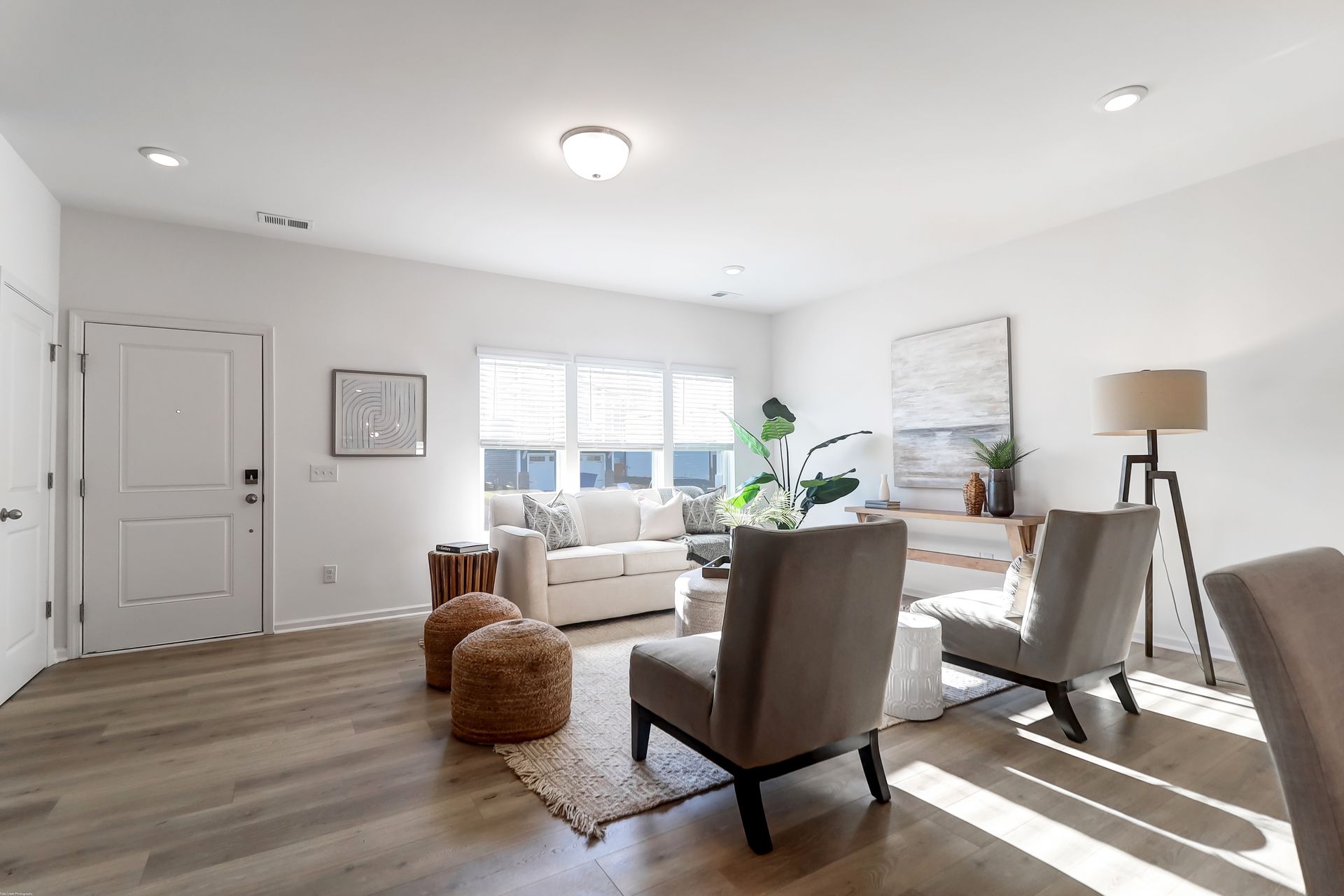A living room with a couch , chairs , ottomans and a lamp.