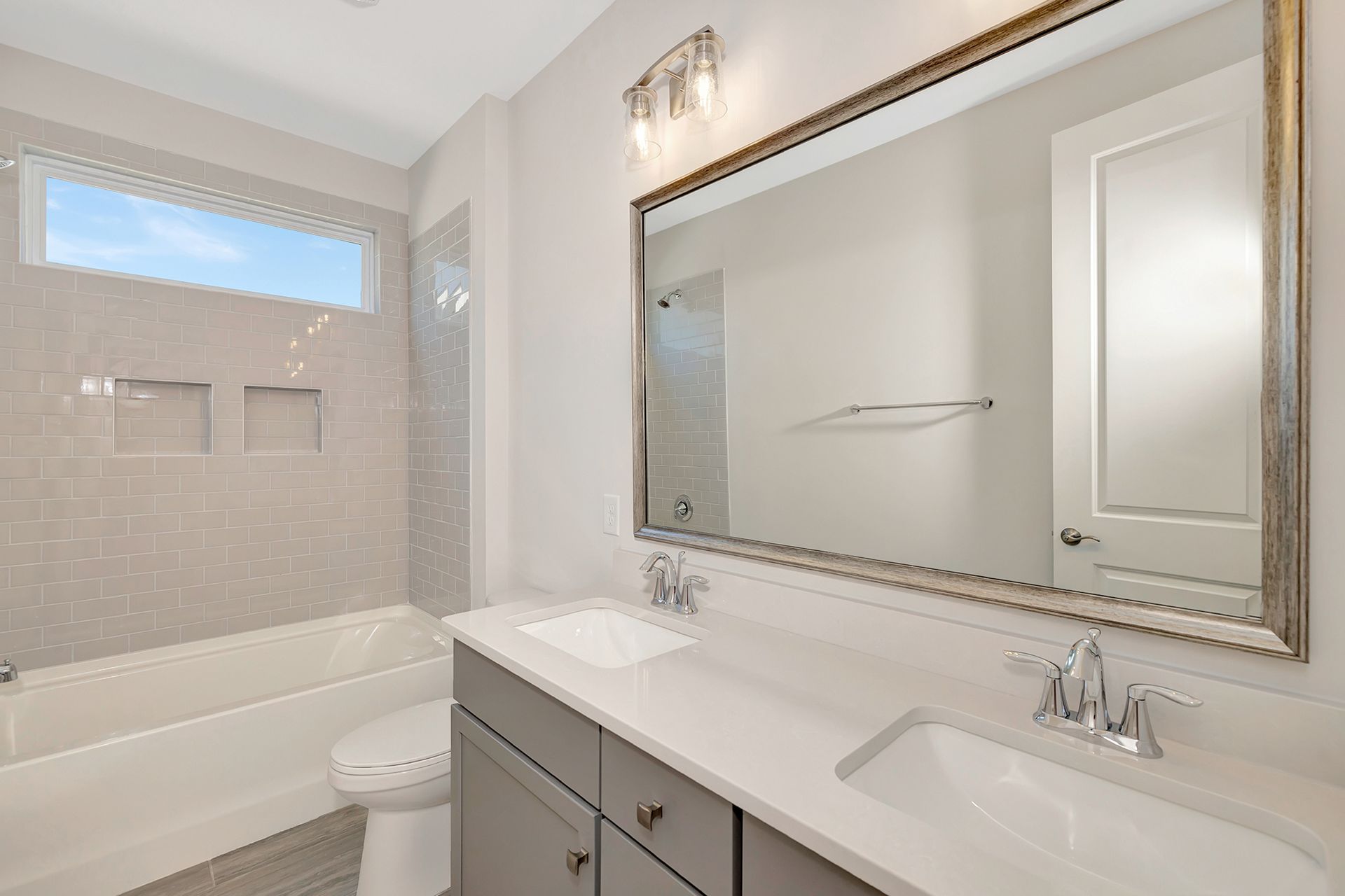A bathroom with a sink , toilet , tub and mirror.